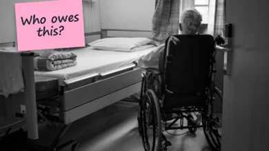 An older person seen from behind in a wheelchair beside an empty bed in a nursing home room, with a sticky note reading “Who owes this?”.