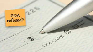 A pen resting on a blank personal check, with a sticky note reading “POA refused?”.
