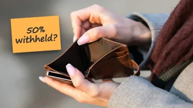 Hands opening an empty brown leather wallet, with a sticky note reading “50% withheld?”.